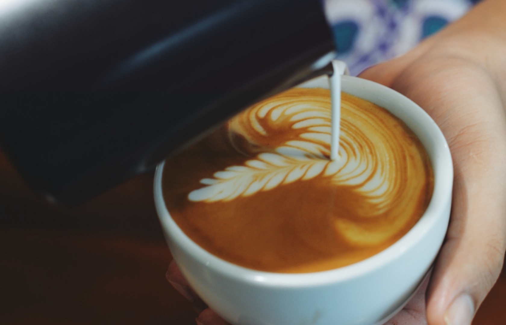 Barista pouring milk into an espresso