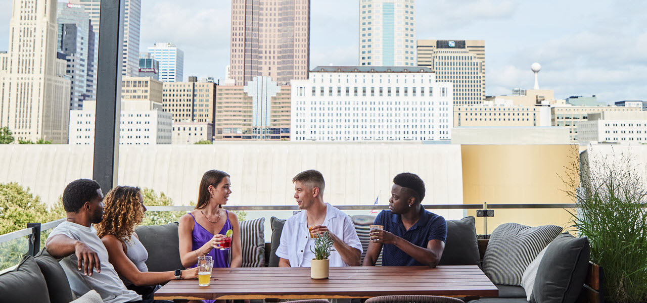 five people sitting at a table on a rooftop patio (banner)