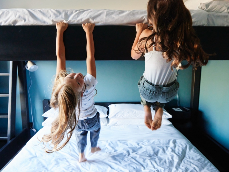 Two female children hanging from bunk bed