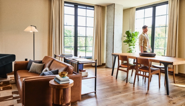 living room with couch, chairs, lighting and dining table with man walking by