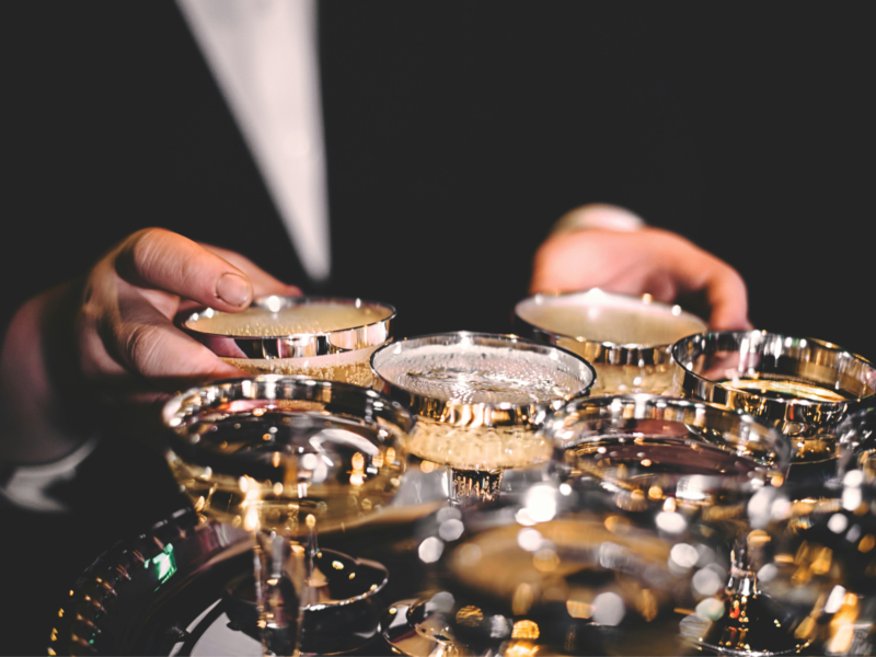 person picking up champagne from tray of glasses