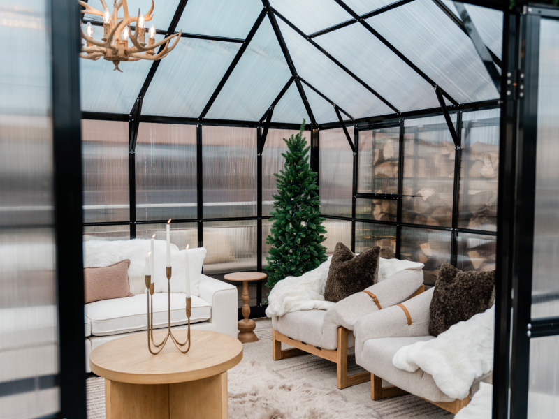 inside of winter greenhouse with cozy furniture and holiday decor