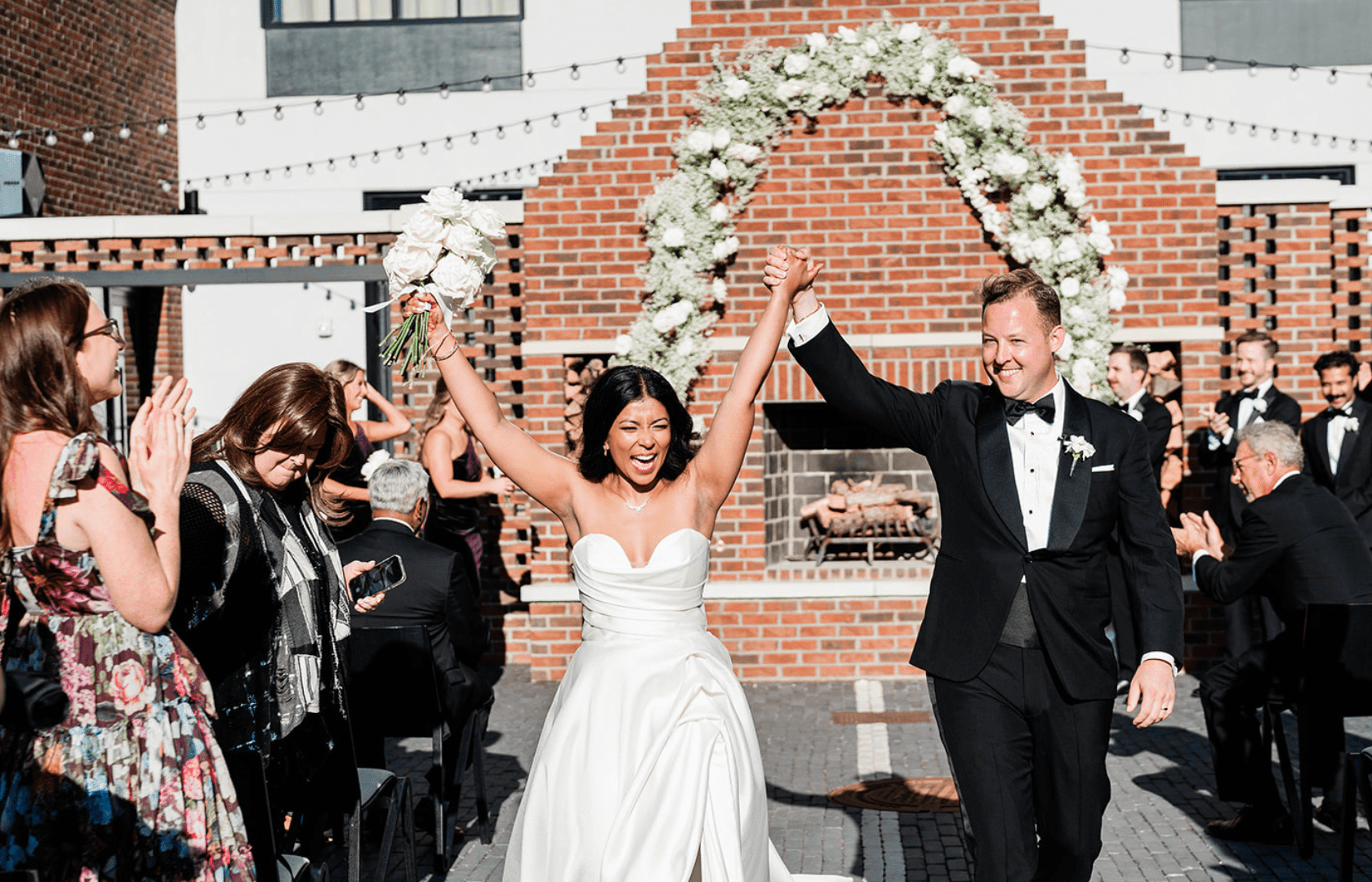 Man and woman walking down aisle holding hands up after getting married