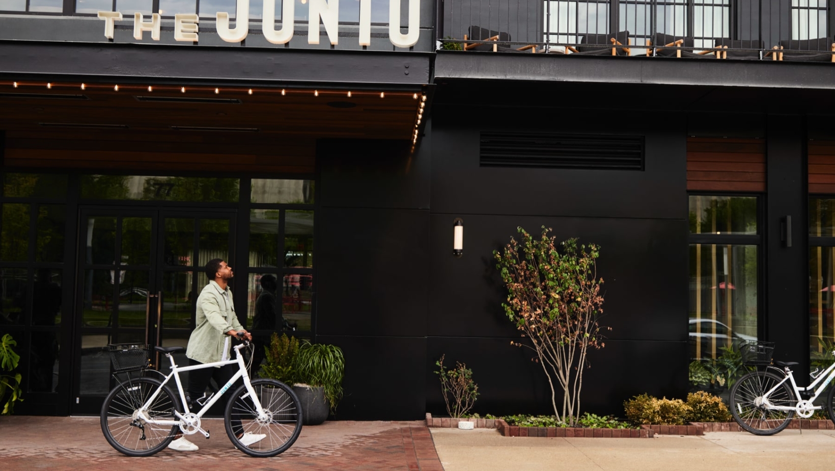 Man walking bike past front of hotel