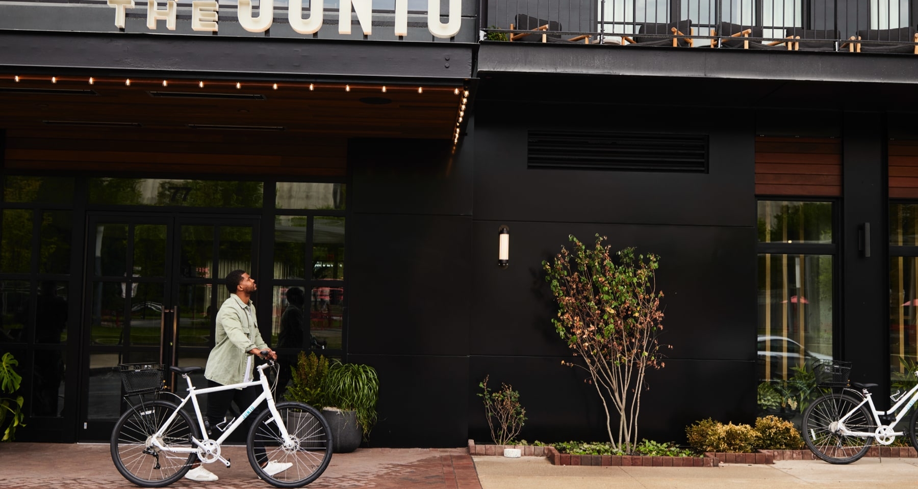 Man walking bike past front of hotel