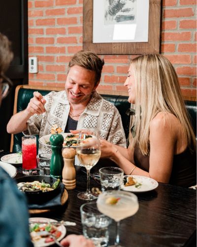 couple eating dinner with a full table of food and drinks