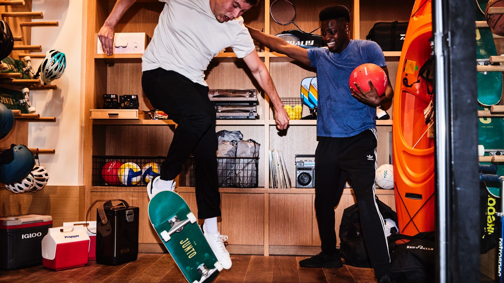 Two guys playing with skateboard and basketball in a shop
