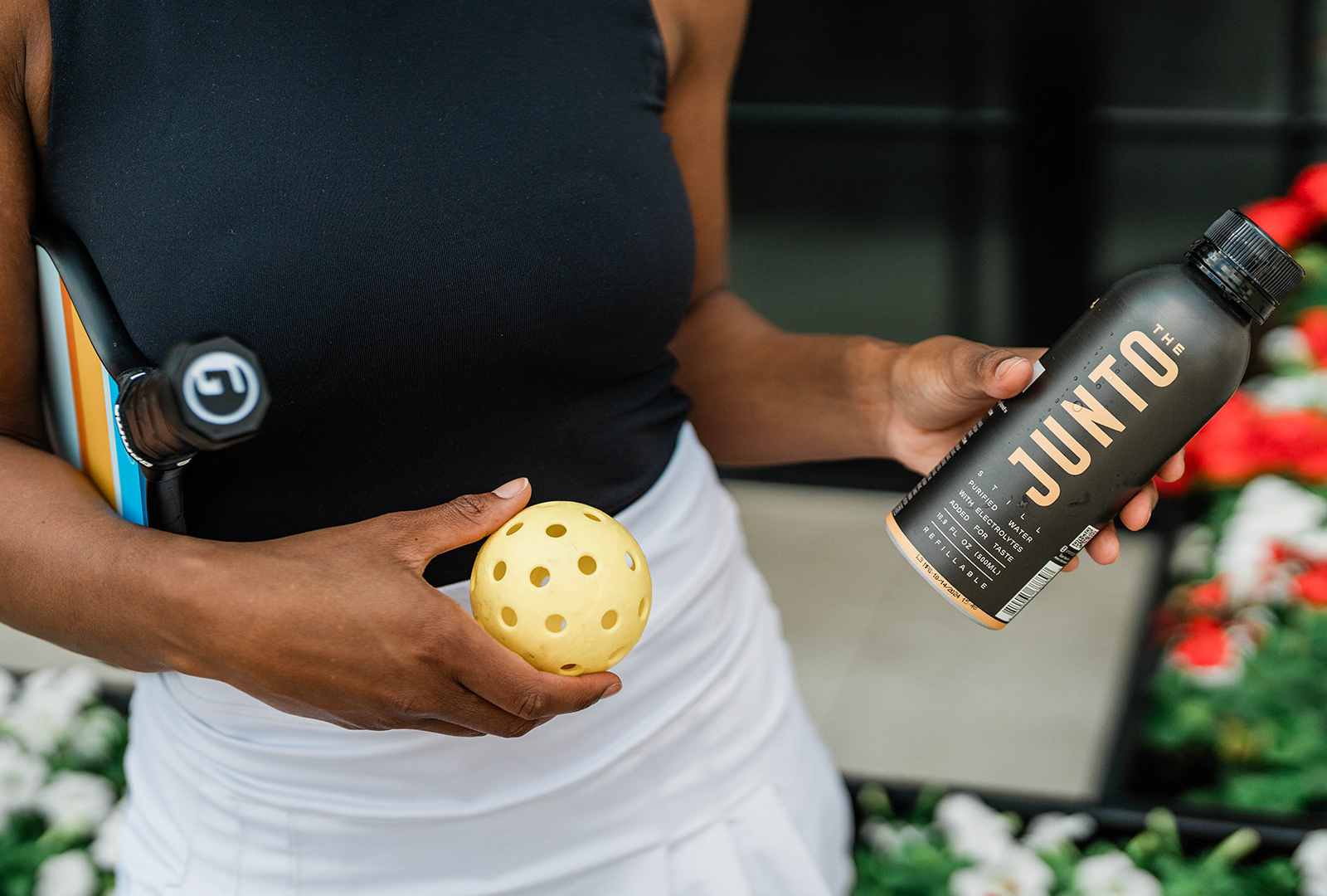 Woman holding pickleball gear and water